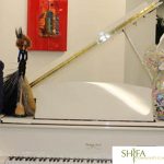 Shifa Clinic celebration at Delegata with two men posing next to white piano